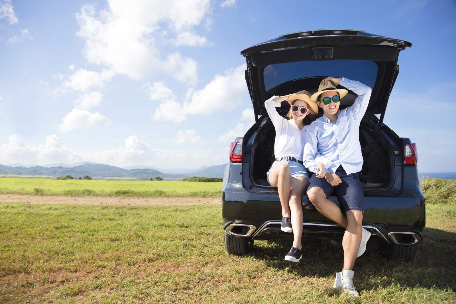 a couple relaxing on their car boot in a rural area