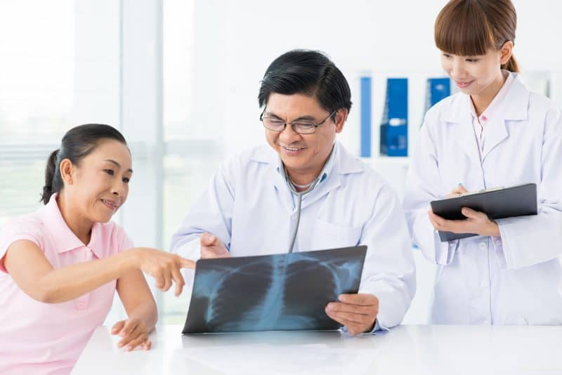 An adult doctor and his nurse examining an x-ray with the patient