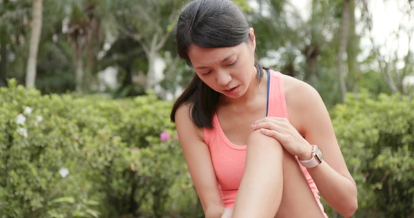 7 Stretches & Exercises for Knee Pain Relief in Minutes 1 A woman experiencing a knee pain