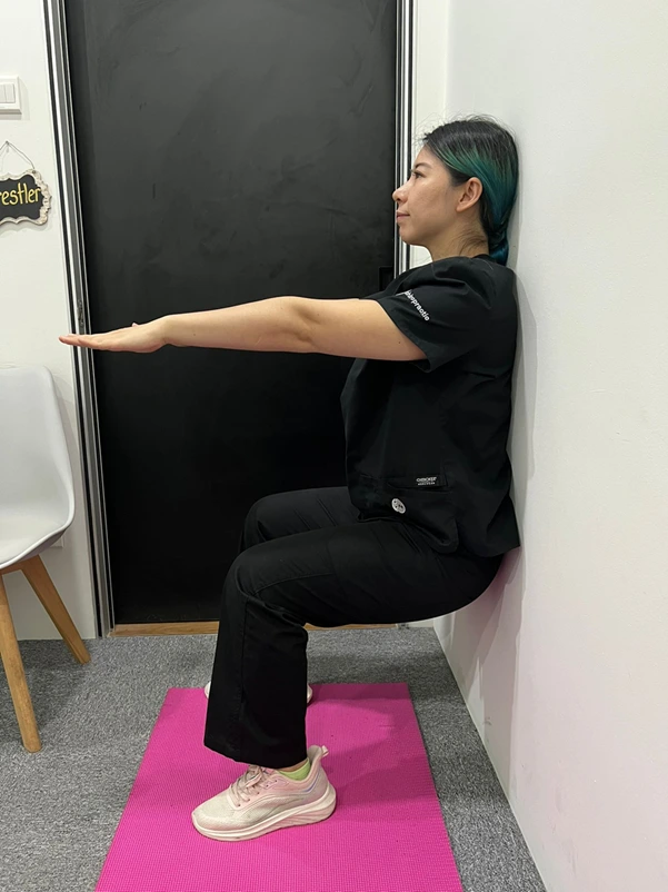 A woman performing a modified wall sit exercise for low-impact knee strengthening A woman performing a modified wall sit exercise for low-impact knee strengthening