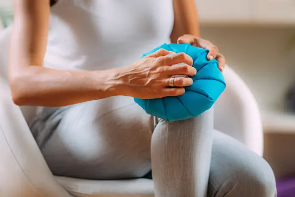 A person applying an ice pack to a knee as an effective home remedy for reducing knee pain and inflammation