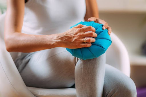 A person applying an ice pack to a knee as an effective home remedy for reducing knee pain and inflammation